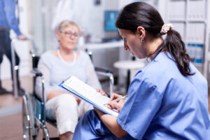 nurse-writing-prescription-disabled-senior-woman-wheelchair-after-medical-examination